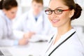 Happy doctor woman with medical staff at the hospital sitting at the table. Red frame glasses Royalty Free Stock Photo