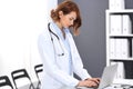 Happy doctor woman at work. Portrait of female physician using laptop computer while standing near reception desk at Royalty Free Stock Photo