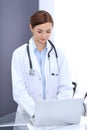 Happy doctor woman at work. Portrait of female physician using laptop computer while standing near reception desk at Royalty Free Stock Photo