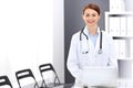 Happy doctor woman at work. Portrait of female physician using laptop computer while standing near reception desk at Royalty Free Stock Photo