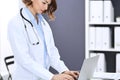 Happy doctor woman at work. Portrait of female physician using laptop computer while standing near reception desk at