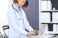 Happy doctor woman at work. Portrait of female physician using laptop computer while standing near reception desk at Royalty Free Stock Photo