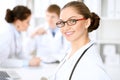 Happy doctor woman with medical staff at the hospital sitting at the table. Red frame glasses Royalty Free Stock Photo