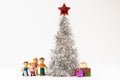 happy doll family with a puppy and colorful gift boxes under the lush silver Christmas tree