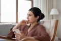 Happy dreamy indian woman resting with cellphone in hands.