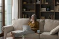 Happy dreamy mature grey haired woman relaxing on couch