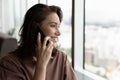 Happy dreamy millennial woman talking on mobile phone