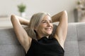 Happy dreamy pretty mature woman resting on comfortable sofa Royalty Free Stock Photo