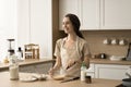 Happy dreamy pretty young woman cooking homemade breakfast in kitchen Royalty Free Stock Photo