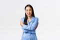 Happy dreamy tender asian girl in blue pajamas, close eyes and smiling as daydreaming, hugging herself, embracing own Royalty Free Stock Photo