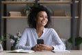 Happy dreamy young african american businesswoman holding cellphone. Royalty Free Stock Photo