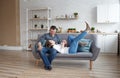 A happy dreamy young Caucasian couple is relaxing on the sofa in the designer living room. The girl is lying on the