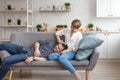 Happy dreamy young Caucasian couple relaxing on the sofa in the designer living room, relaxing hugging.