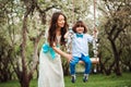 Happy dressy mother and toddler child son having fun on swing in spring or summer park, wearing bow tie and long lacy dress for bi