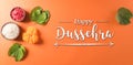 Happy Dussehra. Yellow flowers, green leaf and rice on orange background. Dussehra Indian Festival concept