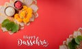 Happy Dussehra. Yellow flowers, green leaf and rice on red background. Dussehra Indian Festival concept