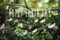 Happy Earth Day text, sign on beautiful anemones flowers in sunny spring woods, selective focus. Springtime. Space for text. Royalty Free Stock Photo