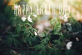 Happy Earth Day text, sign on beautiful anemones flowers in sunny spring woods, selective focus. Springtime. Space for text. Royalty Free Stock Photo