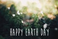 Happy Earth Day text, sign on beautiful anemones flowers in sunny spring woods, selective focus. Springtime. Space for text. Royalty Free Stock Photo