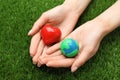 Happy Earth Day. Woman with plasticine planet and decorative heart on green grass, closeup Royalty Free Stock Photo