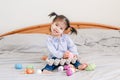 Happy Easter. Asian Chinese baby girl with funny pigtails sitting on bed at home and playing with colorful Easter eggs. Kid child Royalty Free Stock Photo