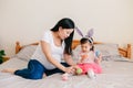 Happy Easter. Asian Chinese pregnant mother with baby girl playing with colorful Easter eggs ona  bed at home. Kid child and Royalty Free Stock Photo