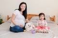 Happy Easter. Asian Chinese pregnant mother with baby girl playing with colorful Easter eggs ona  bed at home. Kid child and Royalty Free Stock Photo