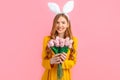 Happy Easter. Happy woman in Easter Bunny ears, girl with a bouquet of tulips, on an isolated pink background Royalty Free Stock Photo