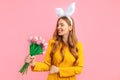 Happy Easter. Happy woman in Easter Bunny ears, girl with a bouquet of tulips, on an isolated pink background Royalty Free Stock Photo