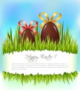 Happy Easter background with chocolate eggs with bows on green grass. Royalty Free Stock Photo