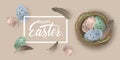 Happy Easter banner with speckled Easter eggs in the nest and feathers on beige background