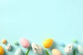 Frame border made of Easter Eggs, bunny, tulips on light blue table. Flat lay, top view Royalty Free Stock Photo