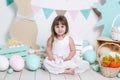 Happy Easter! Beautiful little girl in a white dress with Easter eggs and a basket near the bright decorations. Easter bunny and c