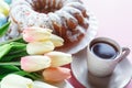 Happy Easter! Big plate with cake and hand painted colorful eggs, tulips and cup of coffee on pink background. Royalty Free Stock Photo