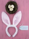 Happy Easter bunny ears with nest on pink wood - vertical.