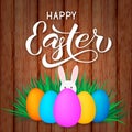 Happy Easter calligraphy lettering. Colorful easter eggs and bunny on wood background. Easy to edit vector template for spring Royalty Free Stock Photo