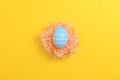 Happy easter celebration holiday. Blue pastel painted eggs in wicker basket nest decoration on a yellow background. Seasonal Royalty Free Stock Photo