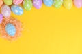 Happy easter celebration holiday. colourful pastel painted eggs in wicker basket nest decoration on a yellow background. Seasonal Royalty Free Stock Photo