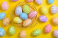 Happy easter celebration holiday. colourful pastel painted eggs in wicker basket nest decoration on a yellow background. Seasonal Royalty Free Stock Photo