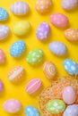 Happy easter celebration holiday. colourful pastel painted eggs in wicker basket nest decoration on a yellow background. Seasonal Royalty Free Stock Photo