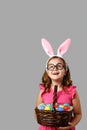 Happy easter. Cheerful little girl in a pink dress with polka dots holds a basket with eggs on a gray background. Royalty Free Stock Photo