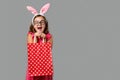 Happy easter. A cheerful little girl in a pink dress with polka dots holds a shopping bag in her hands. Royalty Free Stock Photo