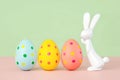 Happy Easter. Close-up of three easter eggs next to easter bunny with copy space for text Royalty Free Stock Photo