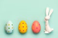 Happy Easter. Close-up of three easter eggs next to easter bunny with copy space for text Royalty Free Stock Photo