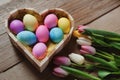 Happy Easter - colored tulips and eggs in a heart shaped bowl