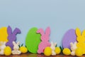 Happy Easter! Colorful Easter bunnies and eggs on blue background with space for text. Purple, yellow, pink artificial decor and