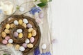 Happy Easter! Colorful easter chocolate eggs in nest, spring flowers, feathers and linen cloth on rustic wooden table. Space for Royalty Free Stock Photo
