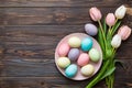 Happy Easter composition. Easter eggs in basket on colored table with yellow Tulips. Natural dyed colorful eggs Royalty Free Stock Photo