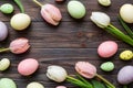 Happy Easter composition. Easter eggs on colored table with yellow Tulips. Natural dyed colorful eggs background top