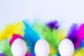 Happy Easter composition with white eggs and colorful feathers on light pastel background. Minimal style, flat lay. Copy space Royalty Free Stock Photo